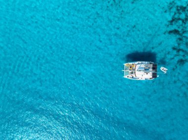 İspanya 'nın Balear Adaları, Mallorca açıklarındaki kristal berrak turkuaz sularda demirli bir yatın havadan görünüşü. Katamaran ve mavi denizin üst drone görüntüsü. Tropik bir manzara. Seyahat