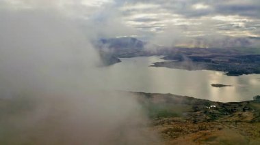 Wanaka, Roys Tepesi 'nden büyüleyici hava manzarası sonbahar manzarasını kaplayan sisi gösteriyor. Huzurlu göl, dramatik dağ zeminiyle çok güzel zıtlaşıyor..