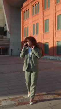 Profesyonel trans kadın dışarıda iş görüşmesi yapıyor, takım elbise giyiyor, şehir ortamında etkili bir şekilde iletişim kurarken özgüven ve kararlılık sergiliyor.