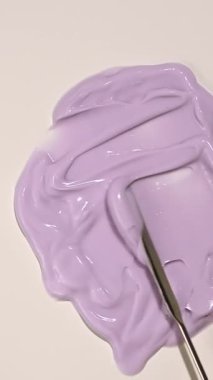 Düz bir yüzeye pürüzsüz, kremsi, mor losyon yayarak zengin ve ipeksi tutarlılığını vurgulayan bir araç ile bir cilt bakım ürününün dokusunu gösteren bir video.