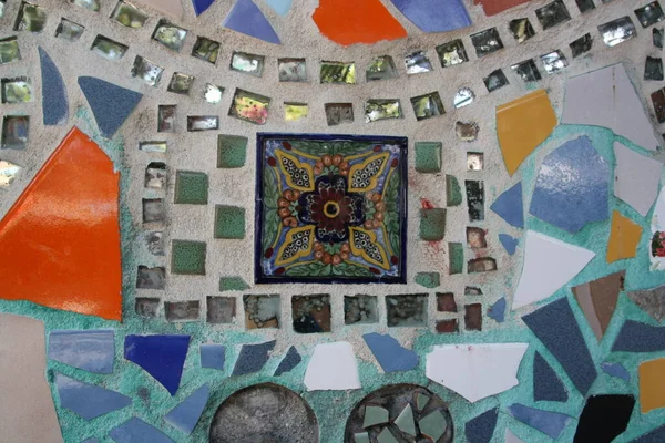 Mosaic art with pieces of mirrors and painted pottery on a wall