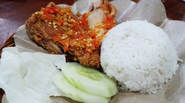 Endonezya yemeği baharatlı acılı kızarmış tavuk pilav ve taze sebzeyle servis edilir.