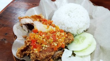 Endonezya yemeği baharatlı acılı kızarmış tavuk pilav ve taze sebzeyle servis edilir.