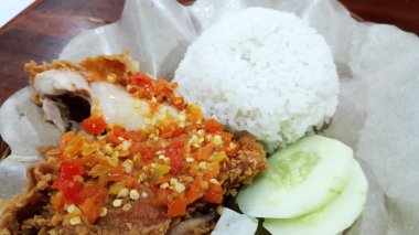 Endonezya yemeği baharatlı acılı kızarmış tavuk pilav ve taze sebzeyle servis edilir.