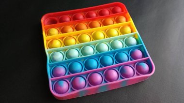 Poppit oyuncağı siyah arka planda, yakın plan. Renkli poppit oyunu