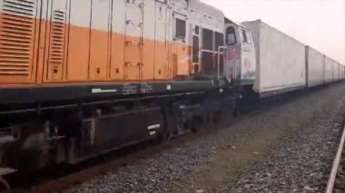 Konteynır kutuları taşıyan tren geçiyor.