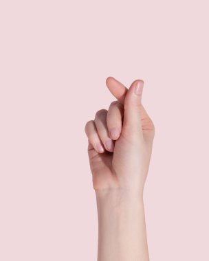 Young woman making heart with her hands on pink background, Korean symbol of love. High quality photo