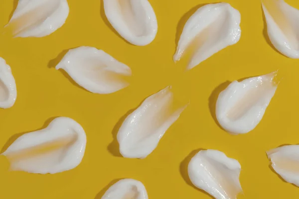 Pattern cosmetic smears of creamy texture on a yellow background