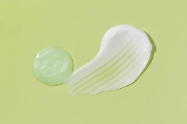 Cosmetic smears cream texture on green background. Beauty serum drop. Skin care products sample.