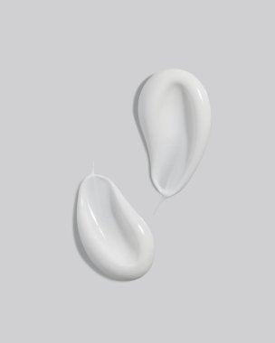 White beauty cream smears smudge on light grey background. Cosmetic skincare product texture. Face cream, body lotion swipe swatch