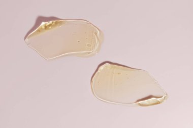 Yellow liquid gel on pink background. Textured smear with oxygen bubbles