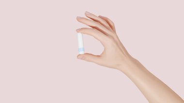 Kadının eli pembe arka planda temiz bir pamuk tampon tutuyor..