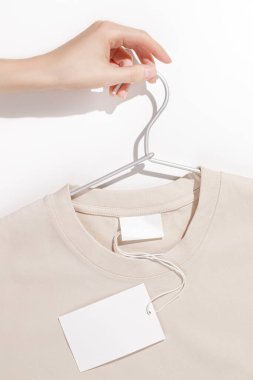 Boş giyim etiketli bej tişört ya da elbise askılığında etiket modeli. Ekoloji konsepti. Kıyafet satışı konsepti