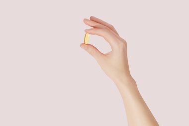 Pembe arka planda takviyeleri (omega 3, vitaminler) elle tutmak