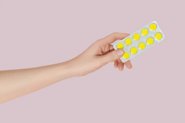 手をピンクの背景にブリスターパックに丸薬を保持 ヘルスケアの概念 — ストック写真