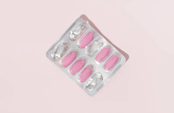 ピンクの背景にピンクの錠剤にサプリメントやビタミンとシルバーブリスター ヘルスケアの概念 トップ表示 — ストック写真