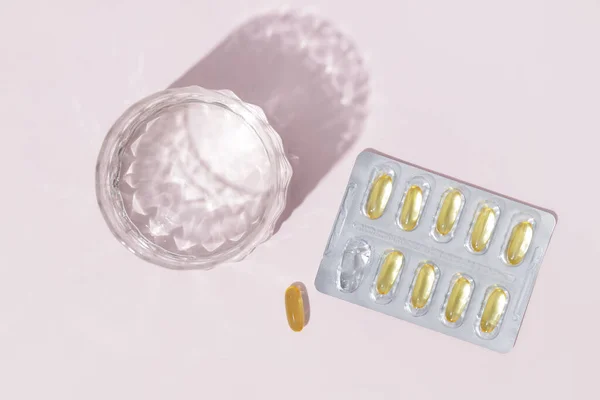 ピンクの背景にブリスターと水のガラスの中の丸薬 ビタミン 健康複合体の治療のための準備 — ストック写真