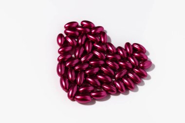 Beyaz arka planda kalp şeklinde tedavi için kırmızı haplar. Reklamcılık ya da diğer fikirler için bir model. Tıbbi ve sağlık hizmeti kavramı