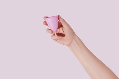 Pembe arka planda regl bardağı olan bir kadın.. 