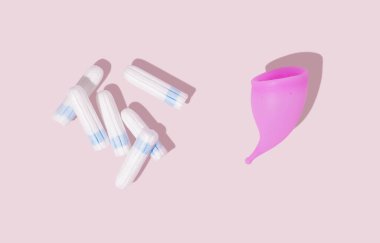 Pembe silikon regl kupası ve pembe arka planda tampon. Üst Manzara. Kadın hijyeni, jinekoloji ve sağlık kavramı