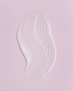 Pembe arka planda beyaz güzellik kremi lekesi. Kozmetik cilt ürünü dokusu. Yüz kremi, vücut losyonu sürgüsü. 