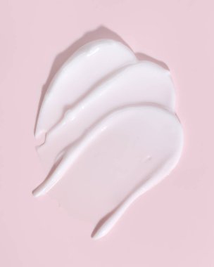 Pembe arka planda beyaz güzellik kremi lekesi. Kozmetik cilt ürünü dokusu. Yüz kremi, vücut losyonu sürgüsü. 