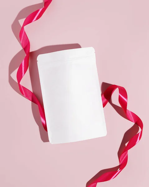 White cardboard packaging for tea with ribbon. Branding and packaging mockup for tea, coffee, snacks on a pink background