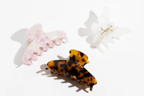 Amber, white and pink plastic hair Claws clips on white background. Hair accessories.