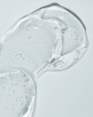 Mavi arka planda şeffaf sıvı jel. Kozmetik cilt ürünü dokusu. Yüz kremi, vücut losyonu sürgüsü.