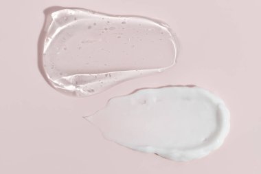 Pastel pembe bir arka planda kremalı makyaj malzemesi. Yüz kremi, vücut losyonu sürgüsü. 