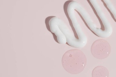 Pembe arka planda çeşitli kozmetik kremler ve serum lekeleri. Güzellik dokusu. Kozmetik ürün örneği.