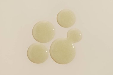 Sarı arka planda sarı serum damlası. Sıvı jel nemlendirici