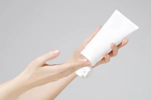 Γυναικεία Χέρια Κρατώντας Κενό Λευκό Πλαστικό Σωλήνα Καλλυντικών Λευκό Φόντο Εικόνα Αρχείου