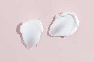 Pembe arka planda beyaz güzellik kremi lekesi. Kozmetik cilt ürünü dokusu. Yüz kremi, vücut losyonu sürgüsü.