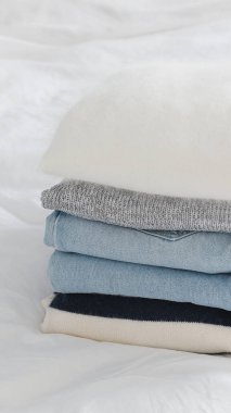 Beyaz bir yatağın üzerinde açık mavi kot pantolon ile düzgünce katlanmış rahat giysiler. Organizasyon gardırobu - boş kopya alanı.