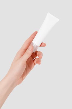 Beyaz arka planda boş beyaz plastik bir tüp tutuyor. Kozmetik güzellik ürünü markalaşma modeli. Boşluğu kopyala
