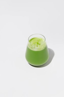 Sıcak yeşil çay, beyaz arka planda toz yeşil çay eşliğinde latte..