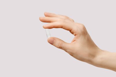 Boş bir şeffaf hap kapsülünü tutan bir insan elinin minimal yakın çekimi. Tıp, ilave, ilaç üretimi veya sağlık hizmetleriyle ilgili kavramsal imaj.