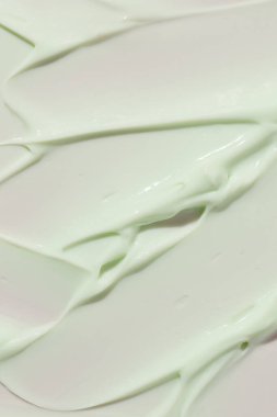 Açık yeşil kozmetik krem ya da cilt ürününün yakın çekim dokusu. Fırça darbeleriyle pürüzsüz nemlendirici yüzey. 