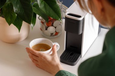 Ev mutfağında kapsül espresso makinesi olan modern sabah kahvesi rutini. Kahve kapsüllerini kullanarak kahve yapmak. Minimum yaşam tarzı, sürdürülebilir yaşam tarzı ve rahat mutfak iç konsepti..