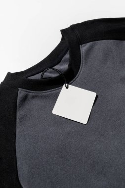 Katlanmış gömleğin üzerindeki boş kıyafet etiketi markalaştırma ya da etiketleme için, arka planda izole edilmiş. Yüksek kalite fotoğraf