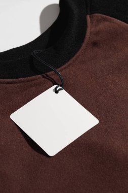 Katlanmış gömleğin üzerindeki boş kıyafet etiketi markalaştırma ya da etiketleme için, arka planda izole edilmiş. Yüksek kalite fotoğraf