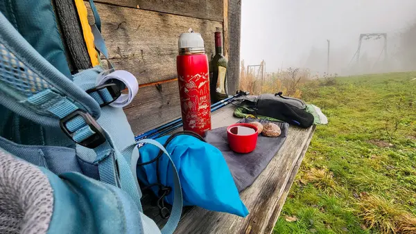 camping with thermos and backpack on the wooden table in the forest.