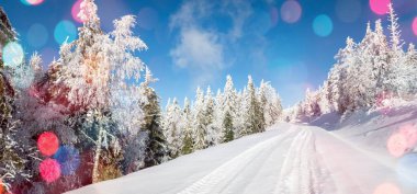 Önplanda parlayan renkli bokeh neşeli bir hava yaratıyor, sıcaklık ve kutlama atmosferi yaratıyor. Arka planda bir kış manzarası mevsimlik cazibenin büyülü bir karışımıyla Noel ve Yeni Yıl 'ın özünü yakalıyor..