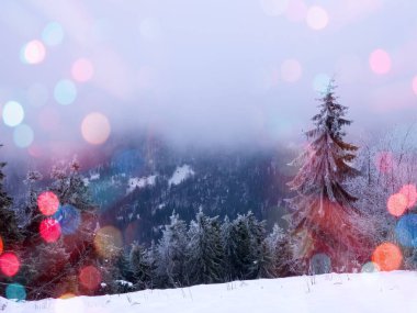 Önplanda parlayan renkli bokeh neşeli bir hava yaratıyor, sıcaklık ve kutlama atmosferi yaratıyor. Arka planda bir kış manzarası mevsimlik cazibenin büyülü bir karışımıyla Noel ve Yeni Yıl 'ın özünü yakalıyor..