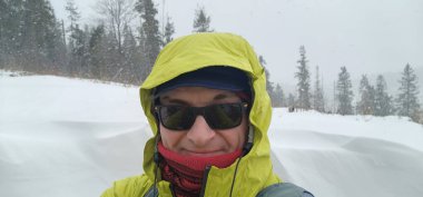 Sarı ceketli ve güneş gözlüklü bir kadın selfie çekiyor.