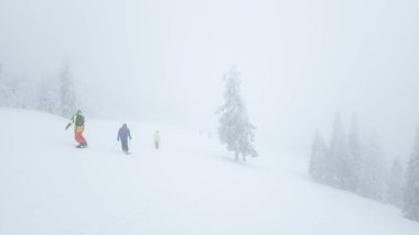 Bir grup insan karla kaplı bir yamaçta kayak yapıyor.