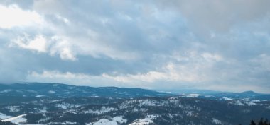 Karlı bir tepede kar kayağı yapan biri.