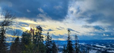 Karlı bir tepede kar kayağı yapan biri.