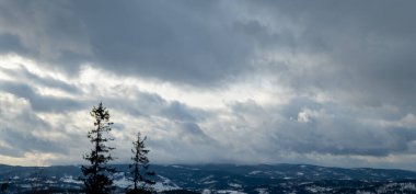 Karlı bir tepede kar kayağı yapan biri.